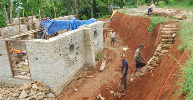 The North face of the new school buildings, facing the Playbank, has playful round windows fashioned from discarded sewer pipe and recycled bottles